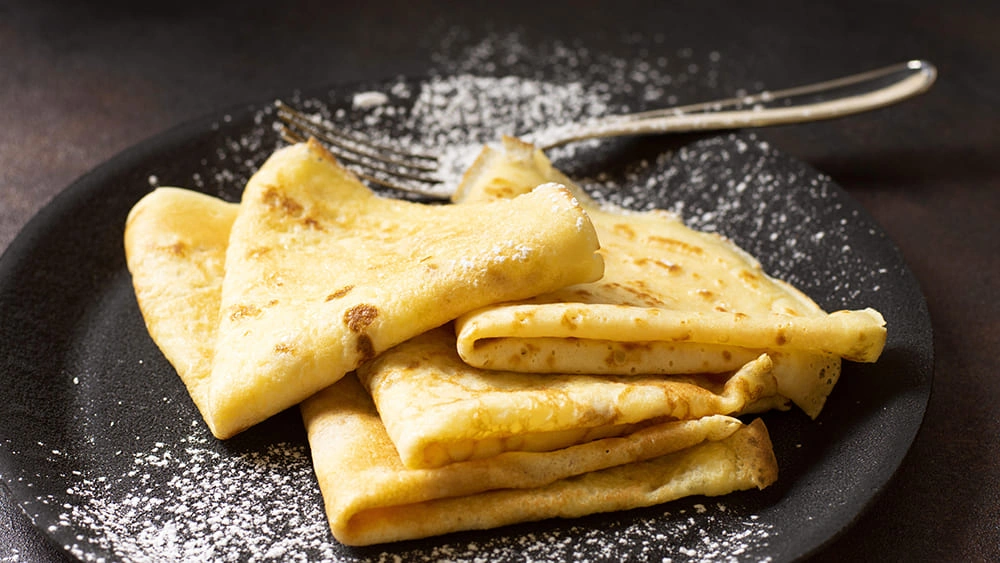 Golden cheese pancakes dusted with powdered sugar, folded and served with High Protein Cottage Cheese in the batter