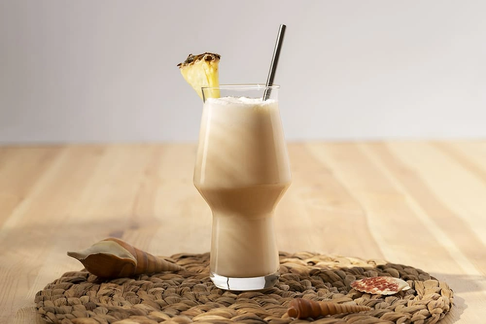 Refreshing smoothie made with High Protein Cottage Cheese, served in a tall glass with a pineapple slice and metal straw.