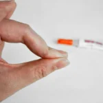Close-up of fingers stuck together due to super glue with glue tube in background