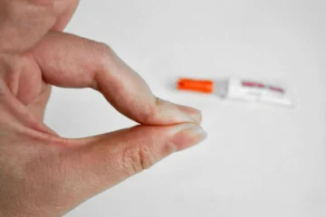 Close-up of fingers stuck together due to super glue with glue tube in background