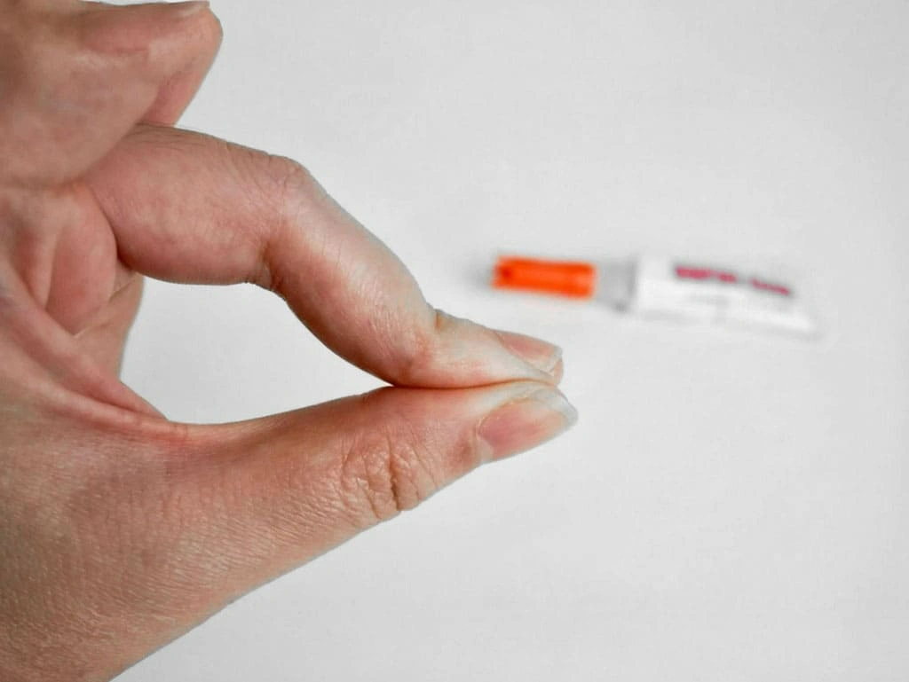 Close-up of fingers stuck together due to super glue with glue tube in background