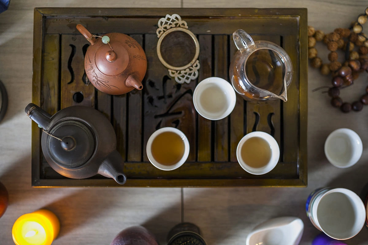 Traditional Chinese tea set with clay teapots and cups on a wooden tray, part of Gongfu tea ceremony